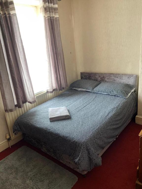 a bedroom with a bed with a blue comforter and a window at 5/6 Bed House Barnsley Centre in Barnsley