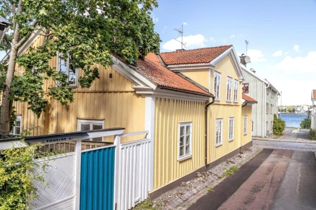 żółty dom z białym płotem obok ulicy w obiekcie Central lägenhet i nyrenoverat 1700-talshus w mieście Västervik