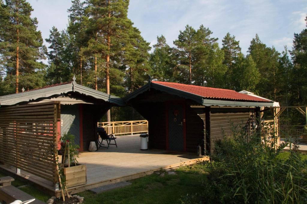 a couple of wooden huts with a deck at Timber cottages with jacuzzi and sauna near lake Vänern in Karlstad