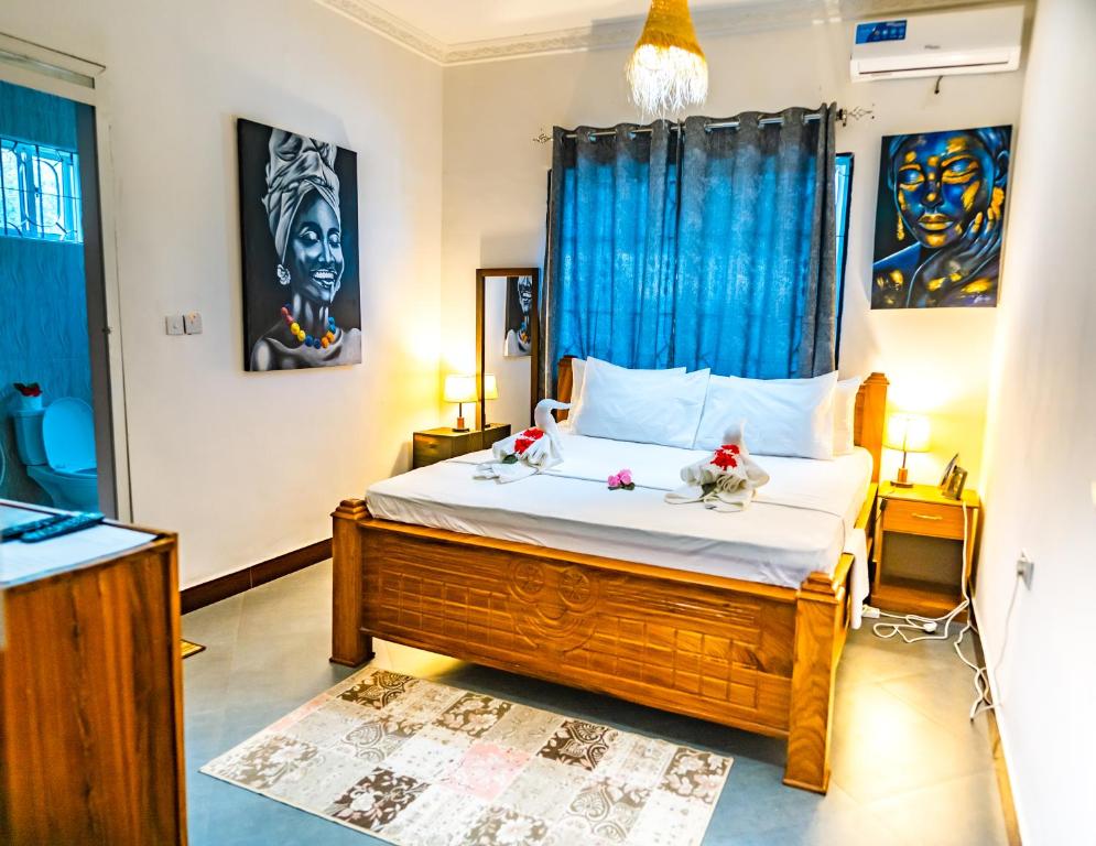 a bedroom with a large bed with blue curtains at Tamu House Pajé Beach in Paje