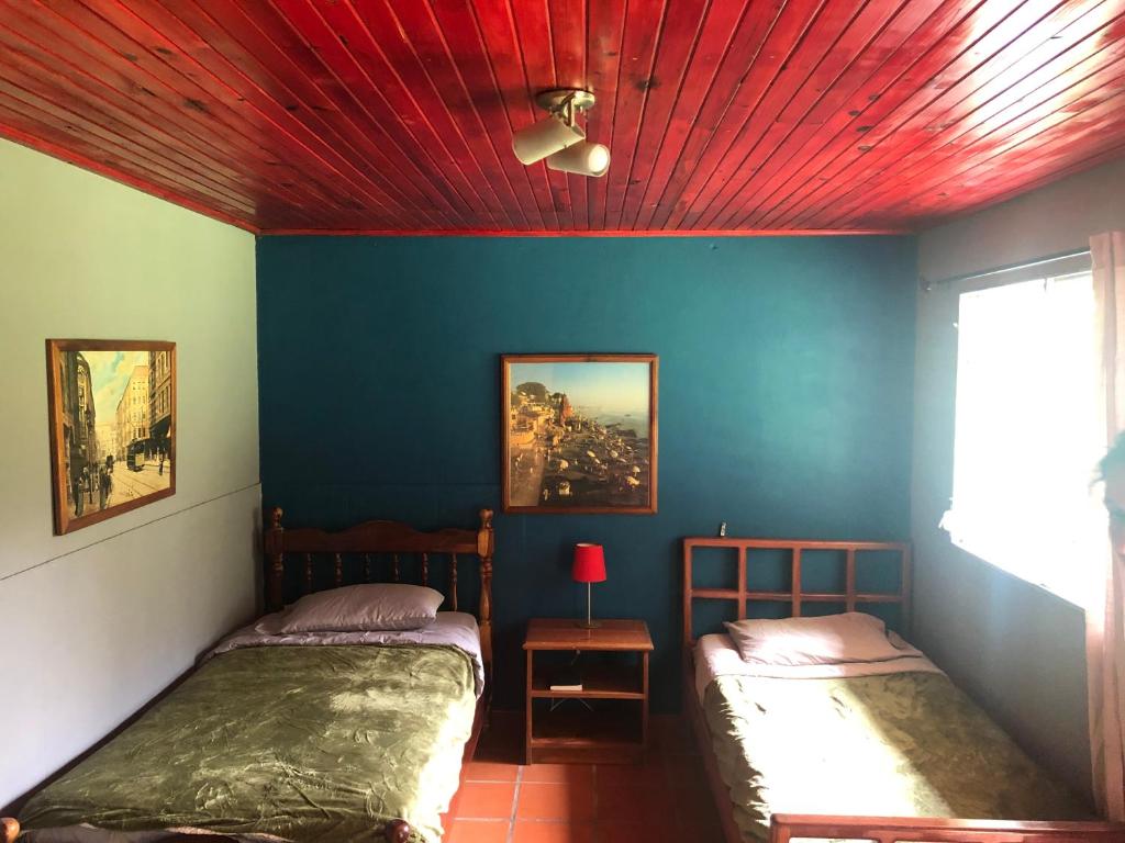 twee bedden in een kamer met een rood plafond bij Toopas in Boquete