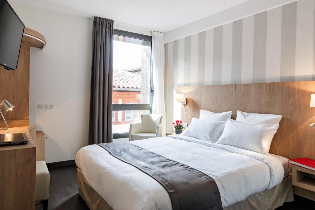 トゥールーズにあるオテル ル ペール レオンの大きなベッドと窓が備わるホテルルームです。