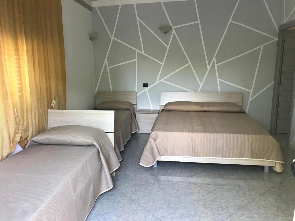 a bedroom with two beds and a geometric wall at B&B The King in Acconia