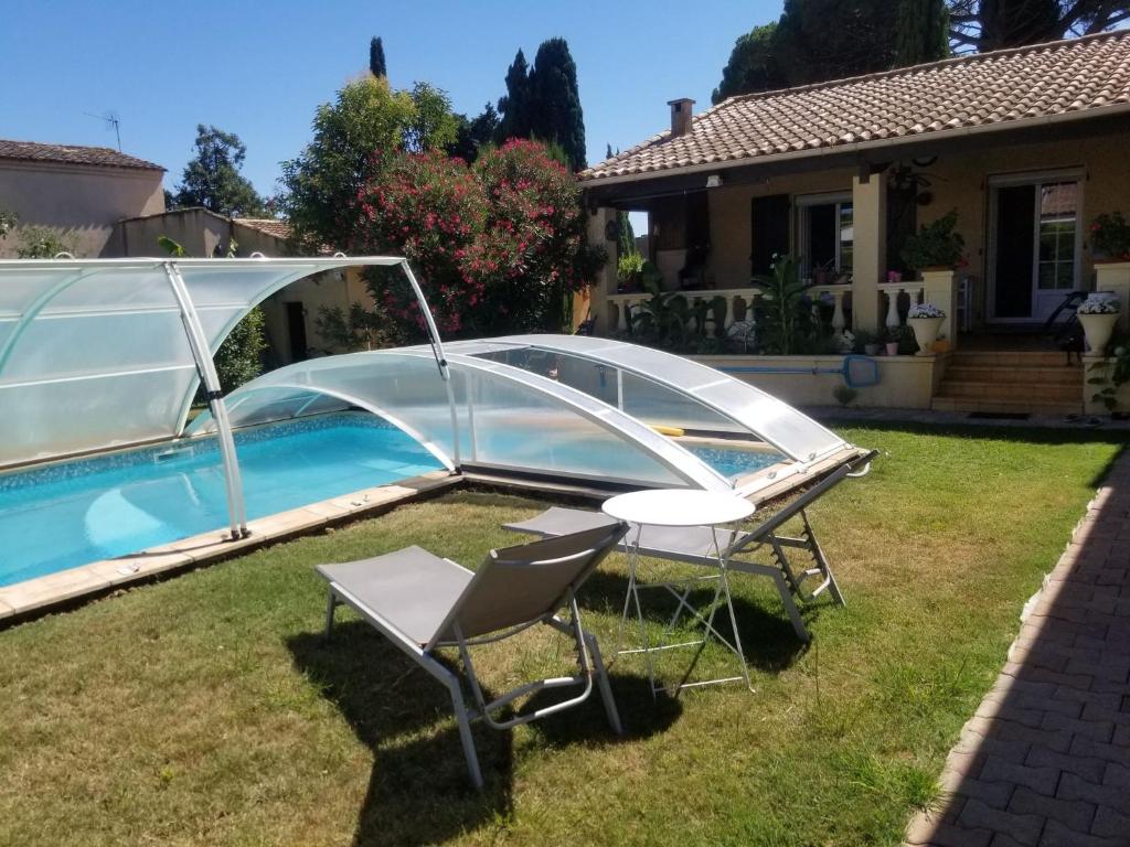 a swimming pool with a cover over a table and chairs at Les Lauriers in Espondeilhan