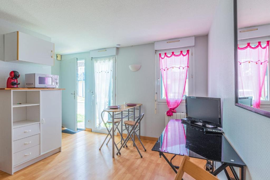 eine Küche mit rosa Vorhängen und einem Tisch im Zimmer in der Unterkunft Studio Flamant - Welkeys in La Rochelle