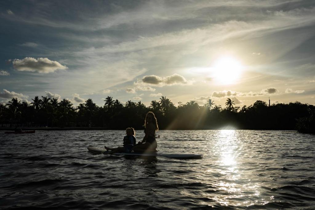 a woman and a child sitting on a paddle board in the water at Fisher Inn Resort & Marina in Islamorada