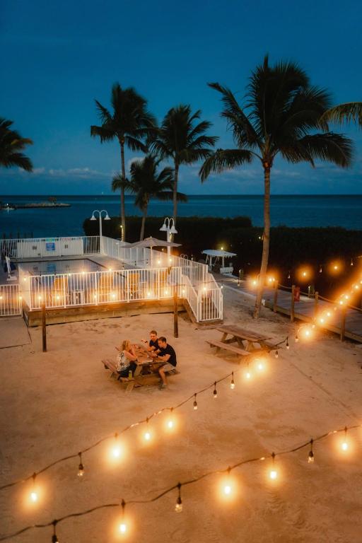 a group of people sitting on a beach at night at Fisher Inn Resort & Marina in Islamorada