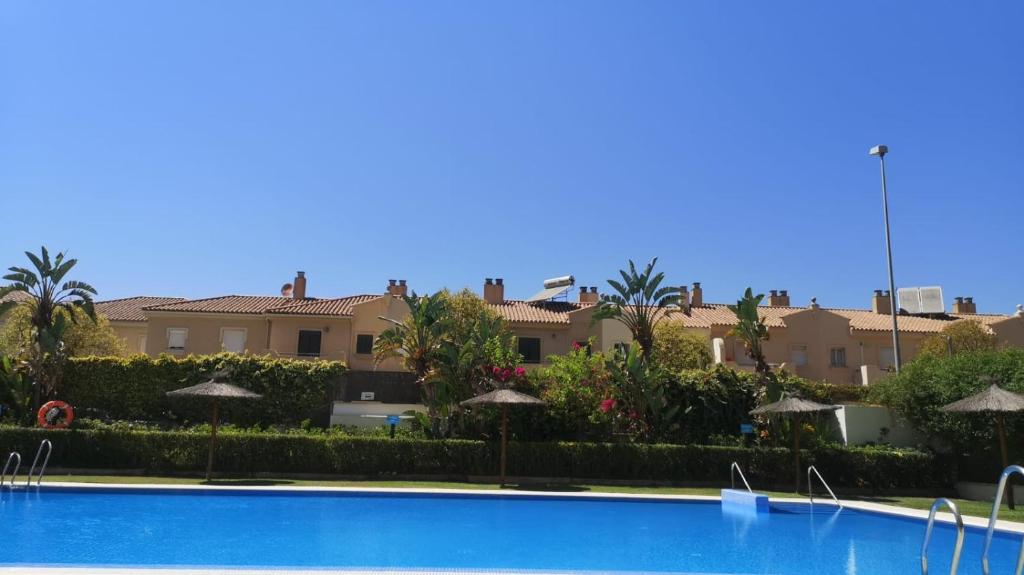 a swimming pool with umbrellas in front of a building at Ático Love in Jerez de la Frontera