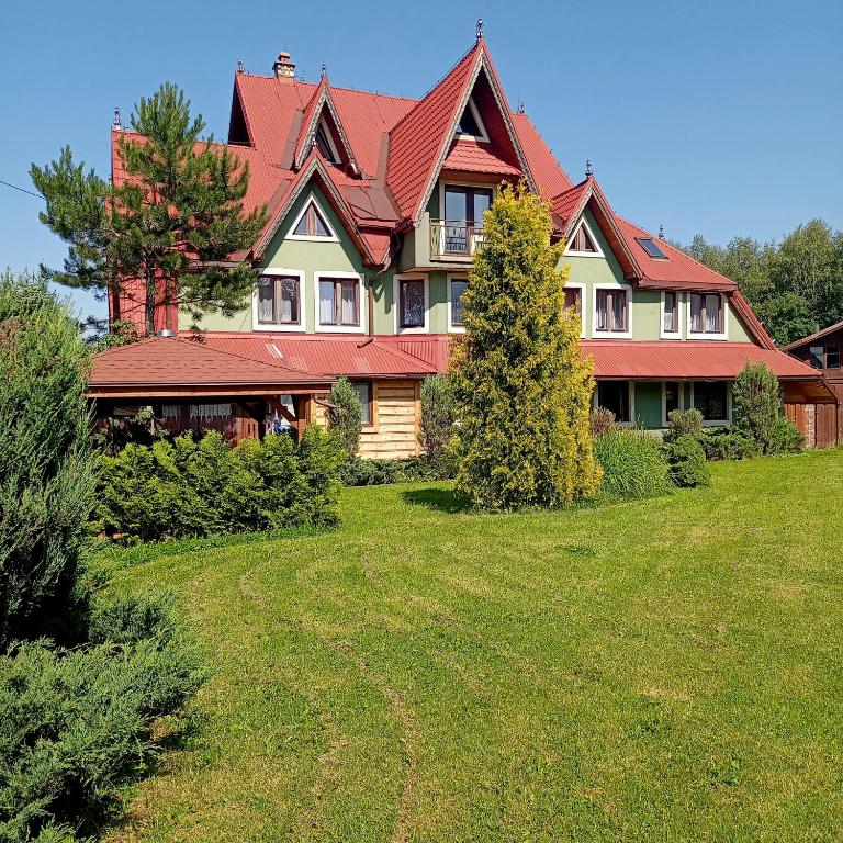 a large house with a red roof on a yard at Kazkowa Koliba in Zakopane