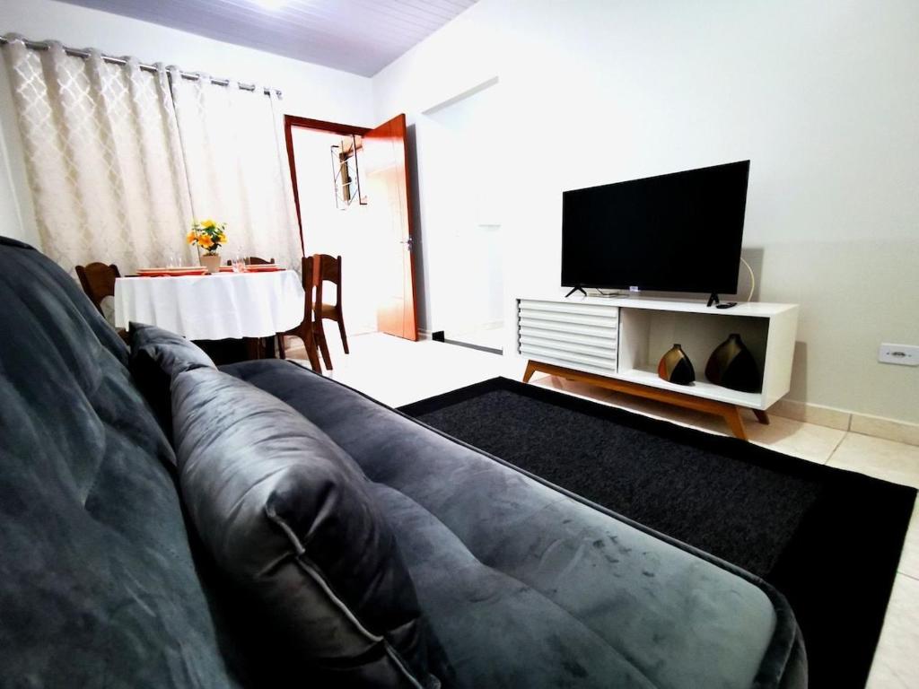 a living room with a couch and a flat screen tv at Casa próxima às Cataratas e Argentina/WIFI/garagem in Foz do Iguaçu