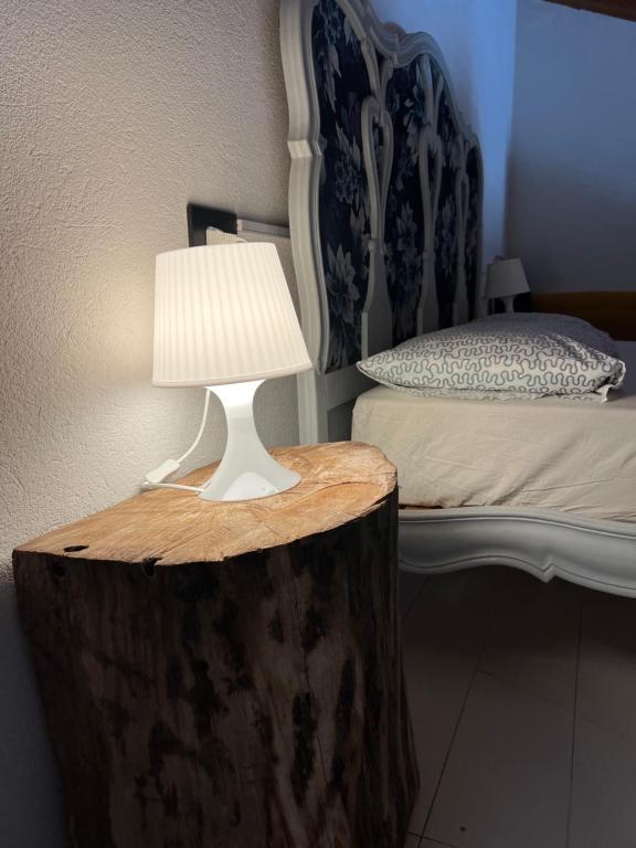 une lampe au-dessus d'une mâchoire d'arbre à côté d'un lit dans l'établissement Il Baco Da Seta, à Manta