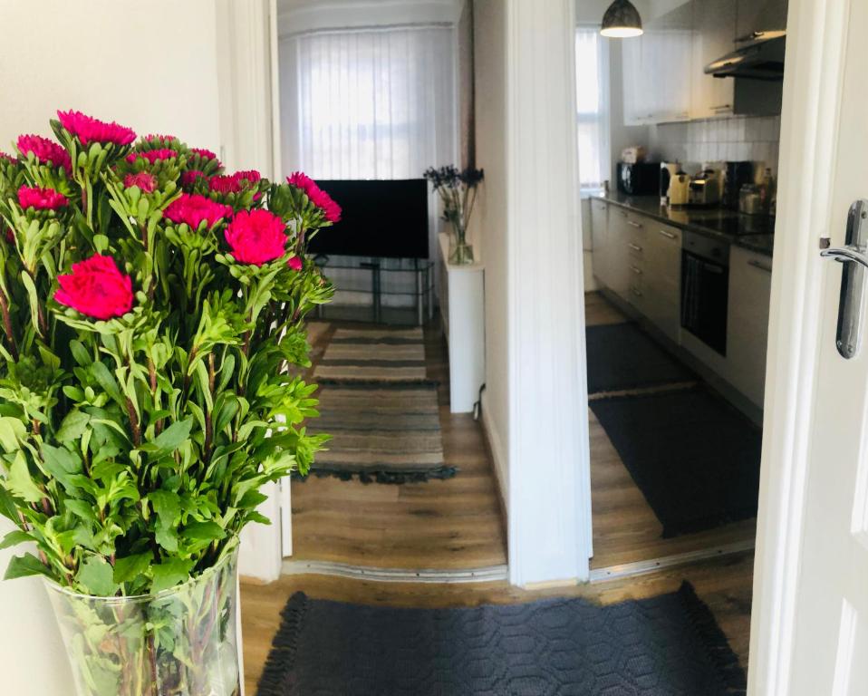 a vase filled with red flowers in a kitchen at Super location 2, 1min metro 10 min from Camden in London