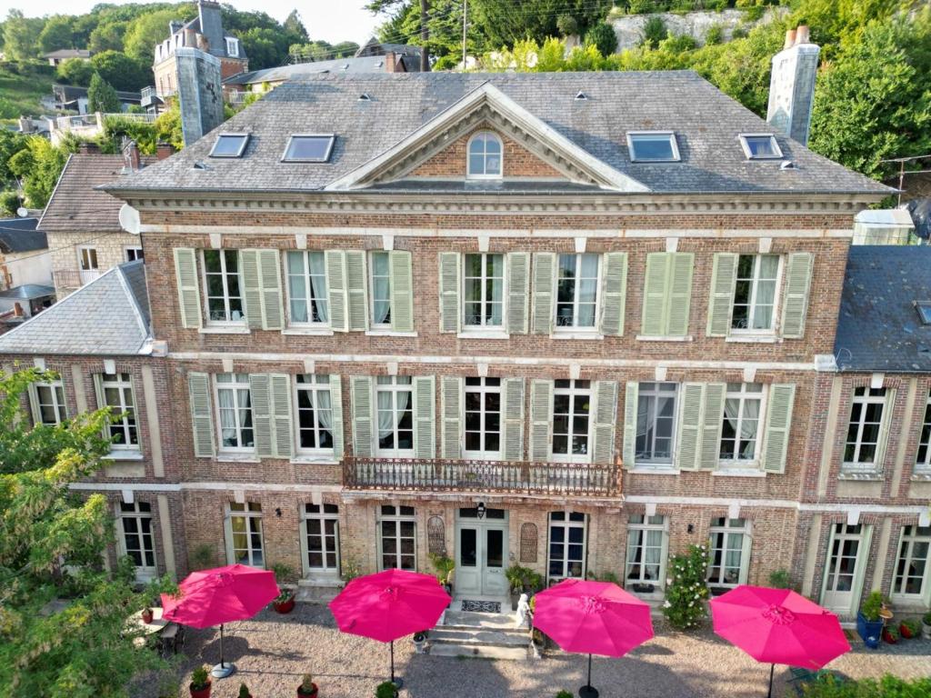 an old house with pink umbrellas in front of it at Demeure en Seine - Gîtes et chambres d'hôte en bord de Seine in Caudebec-en-Caux