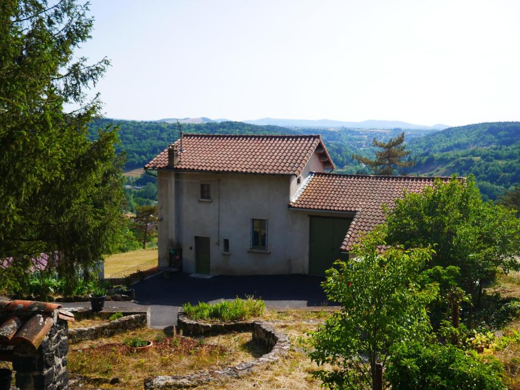 une petite maison blanche avec une porte verte dans l'établissement CHEZ GRAND MAMIE, à Polignac
