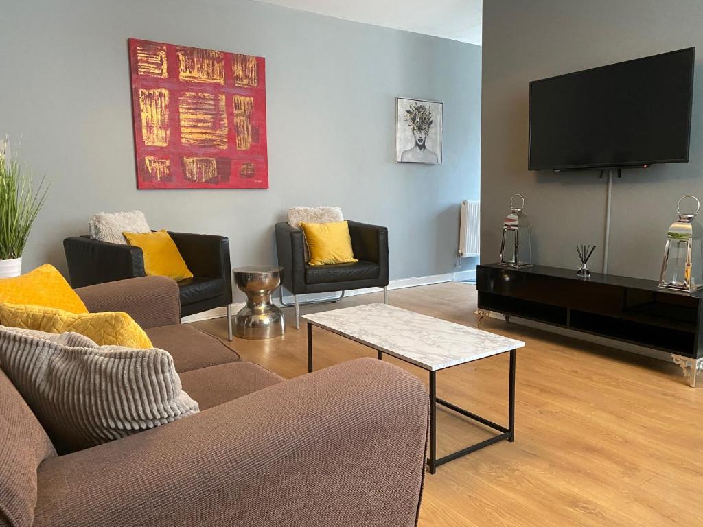 Una sala de estar con sofás y un televisor de pantalla plana. en Pendle House Apartment 1, en Colwyn Bay