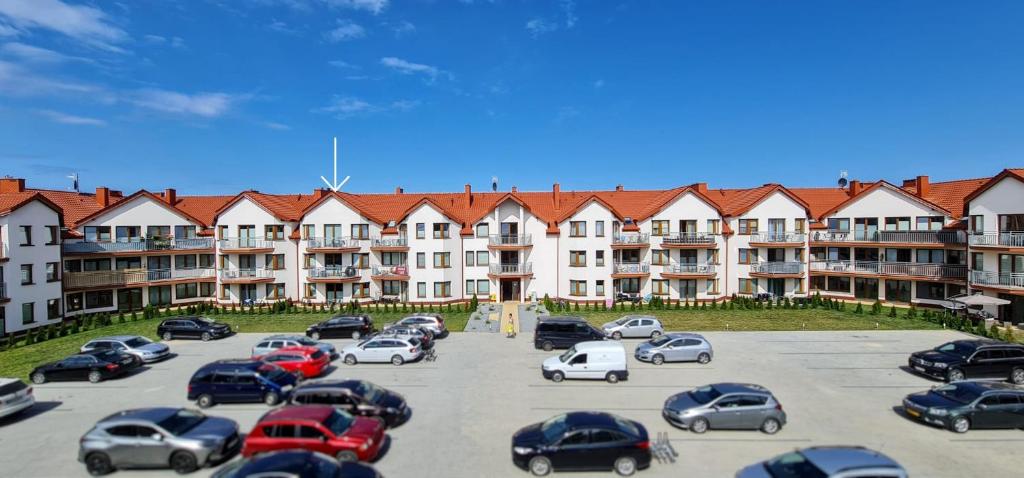 um parque de estacionamento com carros estacionados em frente a um grande edifício em Apartament Baltic Korona B20 em Darłowo