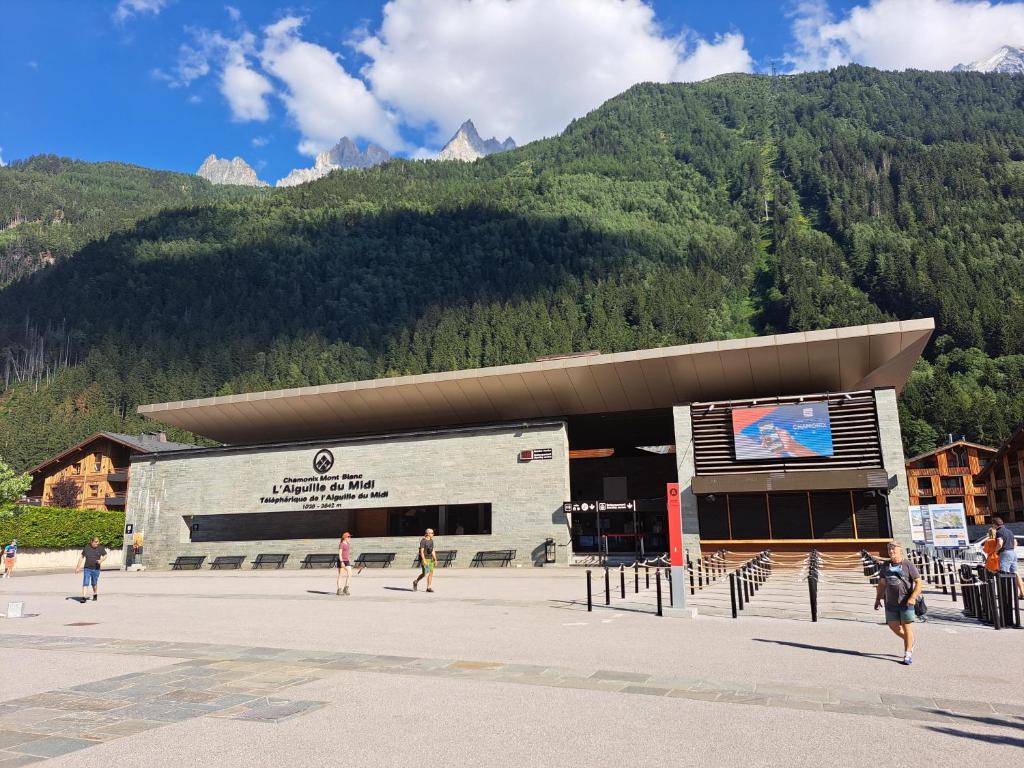 a building with people walking in front of a mountain at Meilleur emplacement hypercentre avec parking privatif souterrain in Chamonix