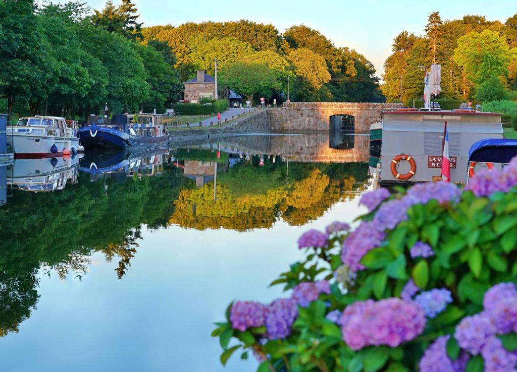 - une vue sur une rivière avec des bateaux et des fleurs dans l'établissement Villa La Côte du Chat 3* en Bretagne romantique, à Hédé