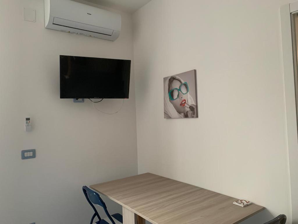 um quarto com uma mesa e uma televisão na parede em NERONE HOUSE em Diamante