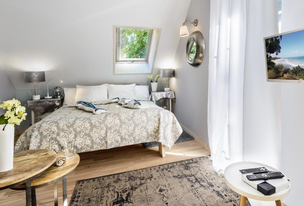 a white bedroom with a bed and a table at Fisher House in Sopot