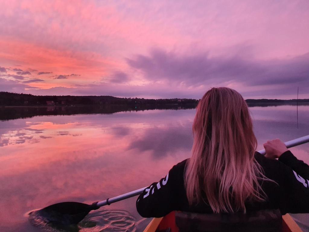 a woman in a canoe on a lake at sunset at Juno Holiday in Mrągowo