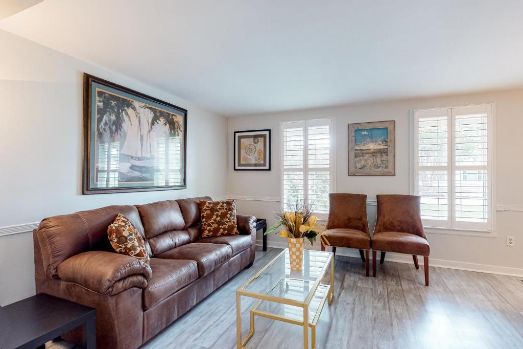 una sala de estar con un sofá de cuero marrón y sillas en Peaceful Pintail, en Ocean Pines