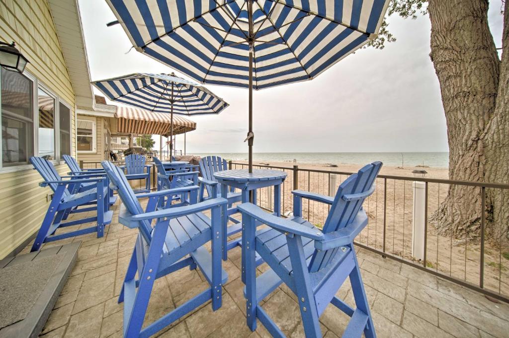 a group of blue chairs and an umbrella on a patio at Sunny, Modern Waterfront Cottage with Grill in Erie! in Erie