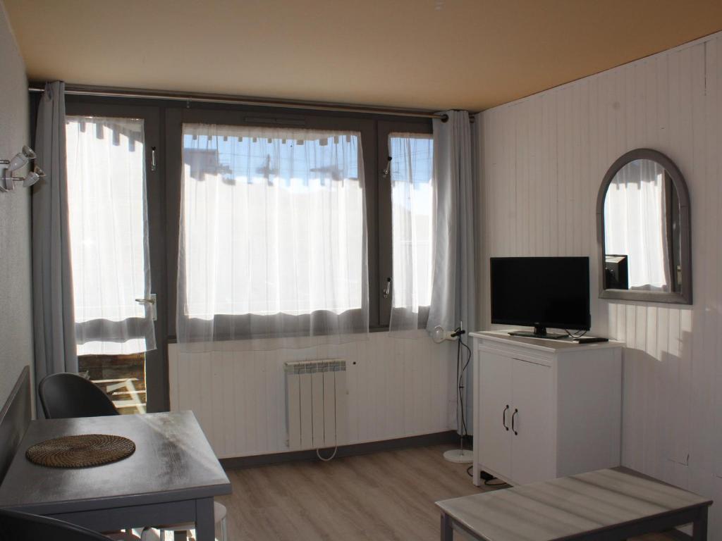 - un salon avec une télévision et 2 grandes fenêtres dans l'établissement Studio 26m² lumineux, balcon sud, pied des pistes, 3-4 pers, commerces sur place - FR-1-181-2587, à Aime La Plagne
