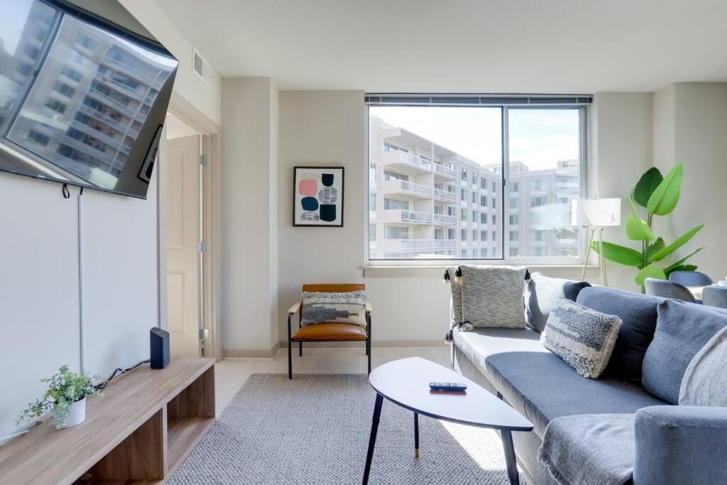 a living room with a blue couch and a tv at Amazing 2BR Condo At Crystal City With Rooftop in Arlington