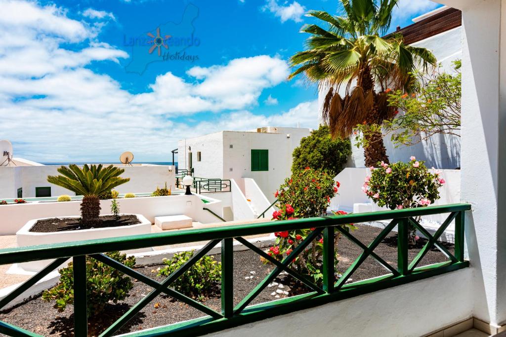 einen Balkon mit Blick auf den Strand und die Palmen in der Unterkunft Vivienda Vacacional Casa Evy in Puerto del Carmen
