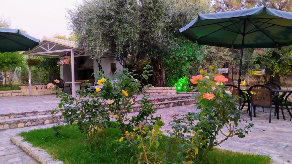 einen Garten mit einem Tisch, Stühlen und einem Sonnenschirm in der Unterkunft Sivota apartments Parthenia in Syvota
