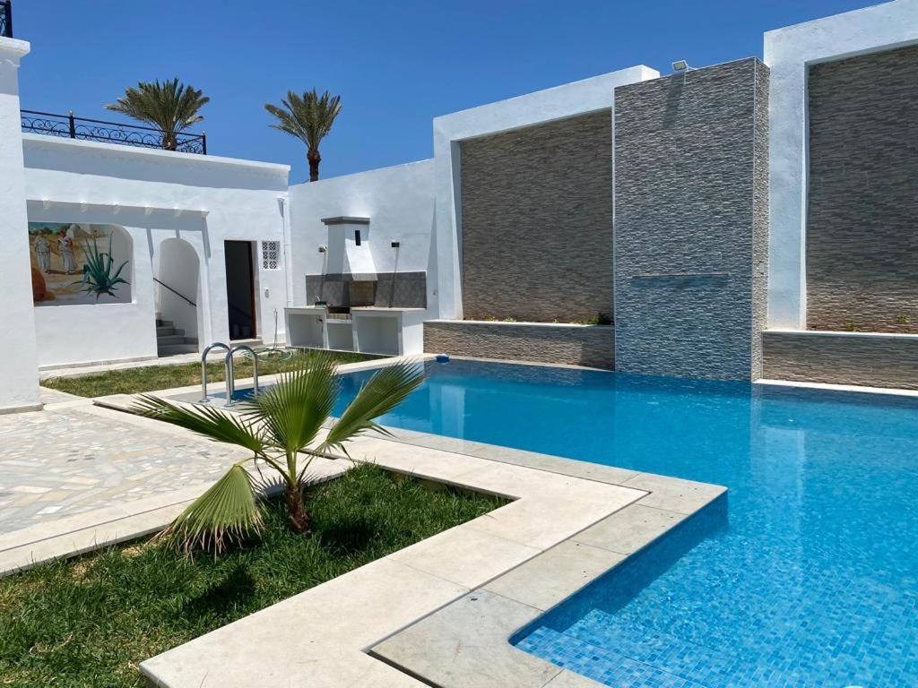 a villa with a swimming pool and a house at La casa blanca in Houmt Souk