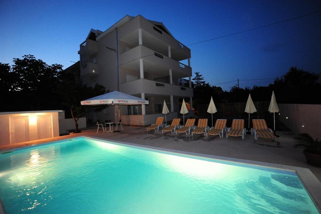 una piscina frente a un edificio por la noche en Apartments Klelija, en Zadar