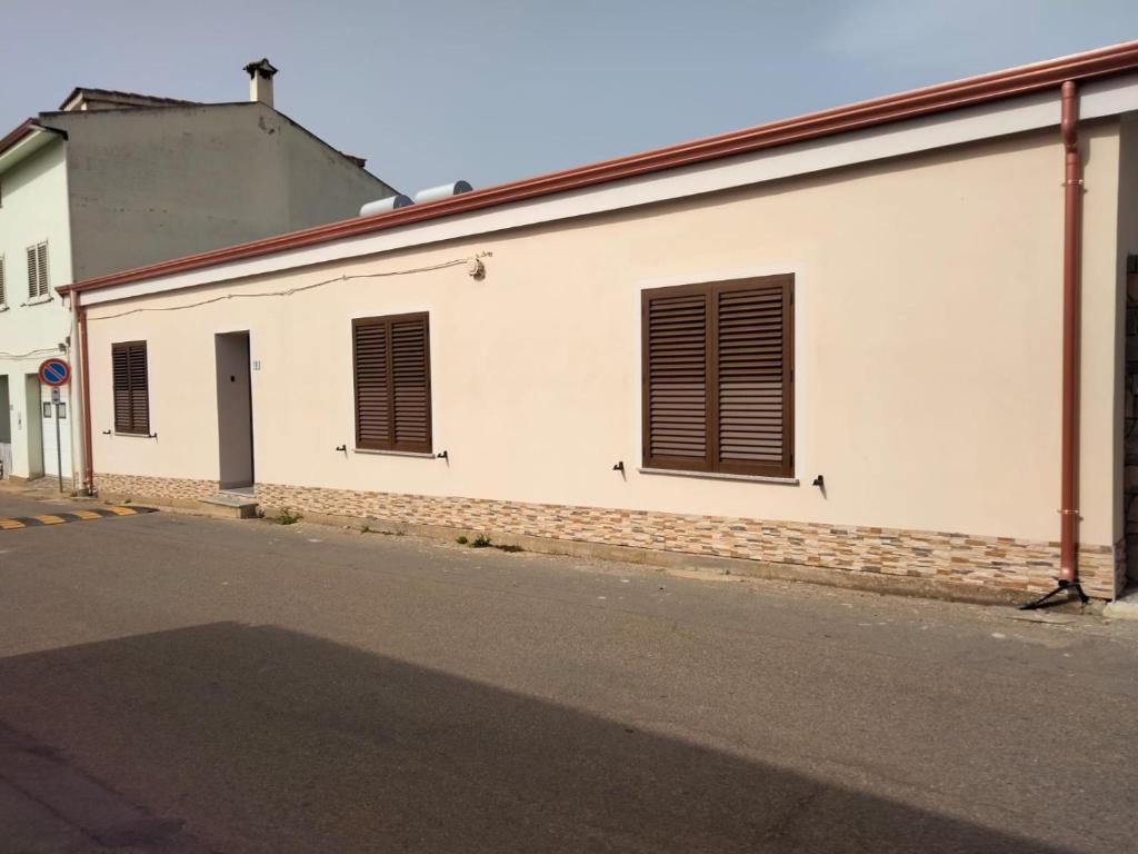 biały budynek z brązowymi okiennicami na ulicy w obiekcie SGM CASA VACANZE w mieście Masainas