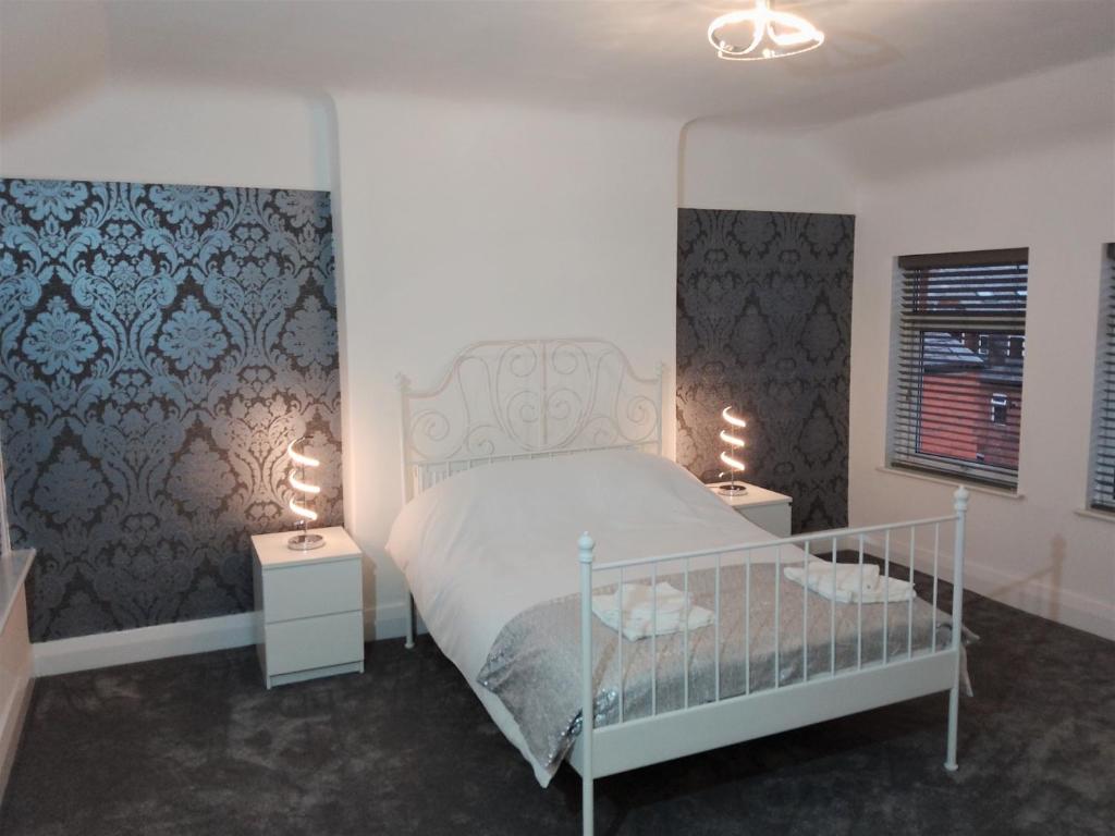 a bedroom with a white bed and two night stands at St Anne's Lodge Apartments Penthouse with Seaview, Lytham St Anne's in Lytham St Annes