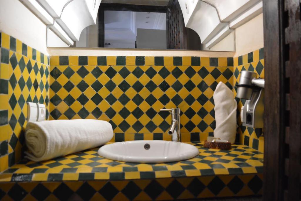 une salle de bains jaune et noir avec lavabo dans l'établissement Dar Riad Niama, à Taroudant