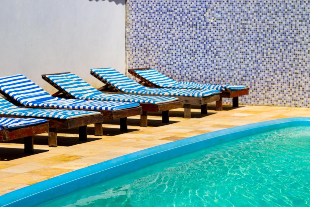 um grupo de cadeiras sentadas ao lado de uma piscina em Pousada Mar do Sonho Vila em Porto de Galinhas