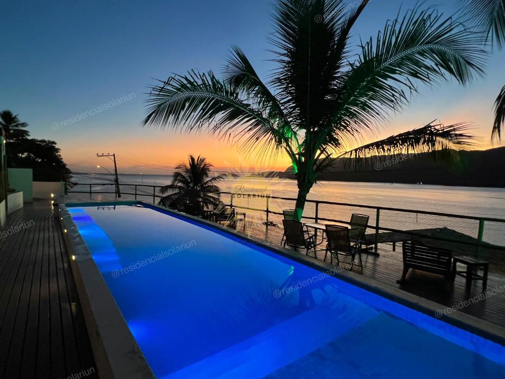 a swimming pool with a view of the ocean at sunset at Residencial Solariun Ilhabela in Ilhabela