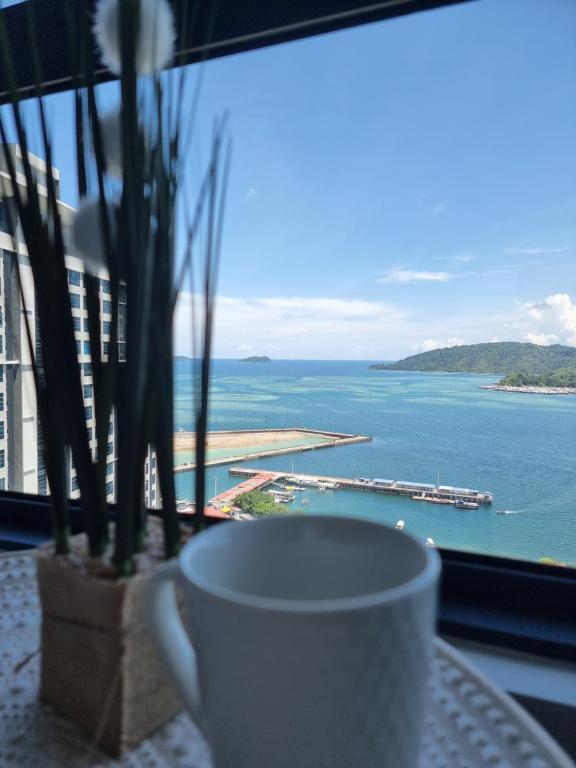 a coffee cup sitting on a table with a view of the ocean at Nana Homestay - Jesselton quay in Kota Kinabalu