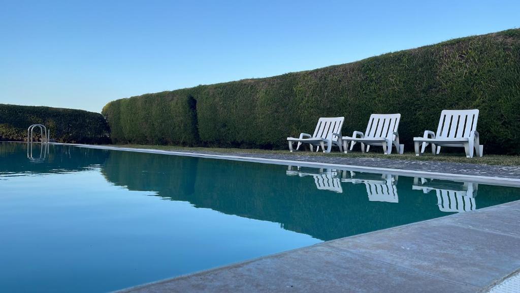 two white chairs sitting next to a swimming pool at Villa Baleia, São Julião Beach - Ericeira in Ericeira