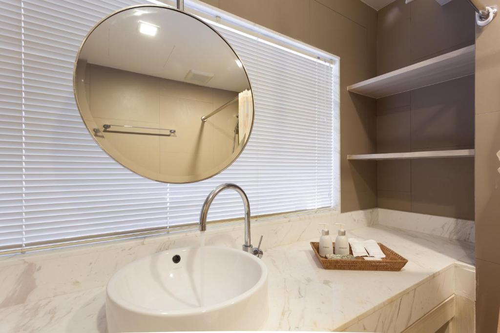 a bathroom with a white sink and a mirror at Coral Inn in Karon Beach