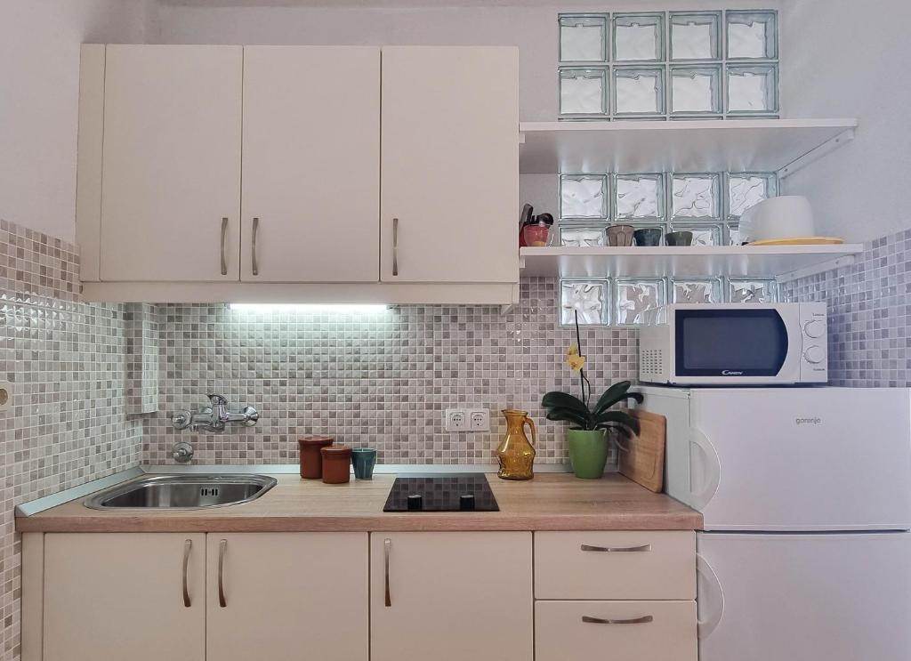 kuchnia z białymi szafkami, zlewem i lodówką w obiekcie Studio Vrboska 540a w mieście Vrboska