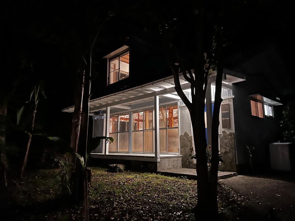 una casa illuminata di notte con finestre e un albero di Oku Cottage - walk to Ohama Beach - Max 4 ppl a Shimoda