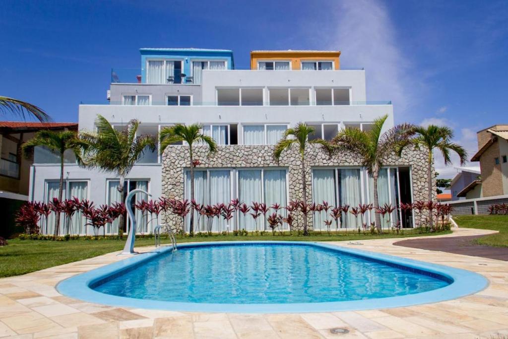 uma casa com piscina em frente a um edifício em CARNEIROS EXPERIENCE! Conforto e Pé na areia! em Tamandaré
