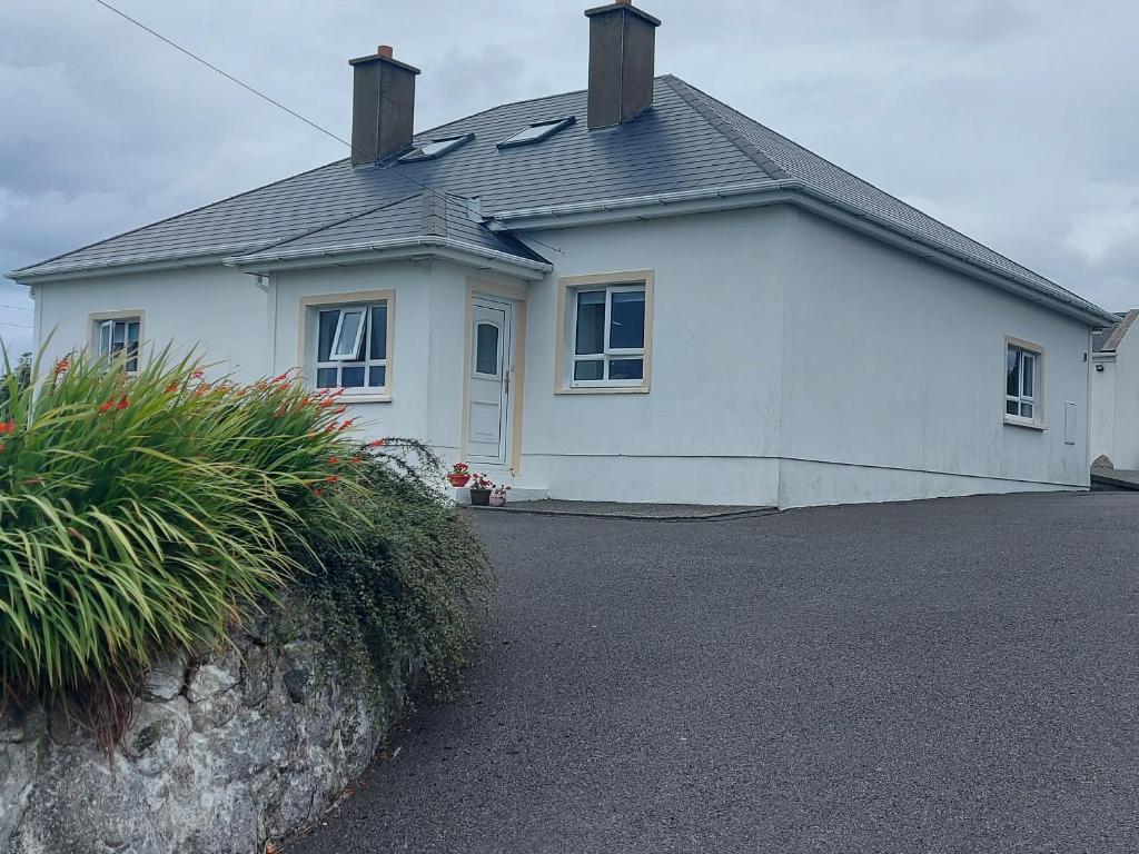 a white house with a driveway in front of it at Ard an Phíobaire in Doirí Beaga