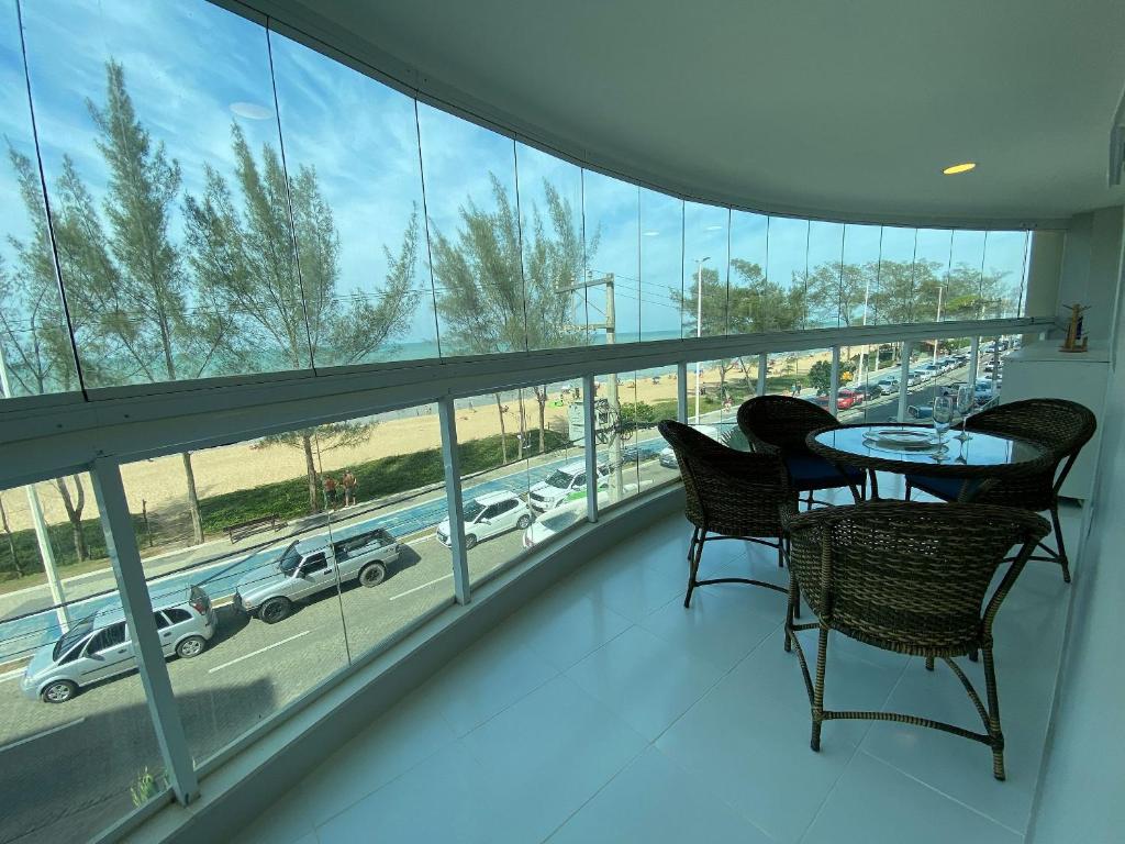 een balkon met een tafel en stoelen en uitzicht op een parkeerplaats bij Apto com VISTA ESPETACULAR a BEIRA MAR no Pecado - Wi Fi 200 mb - 2 Quartos - Garagem - TV Smart - Piscina - Sauna - Ar condicionado - Portaria 24h - Churrasqueira - Cozinha equipada in Macaé