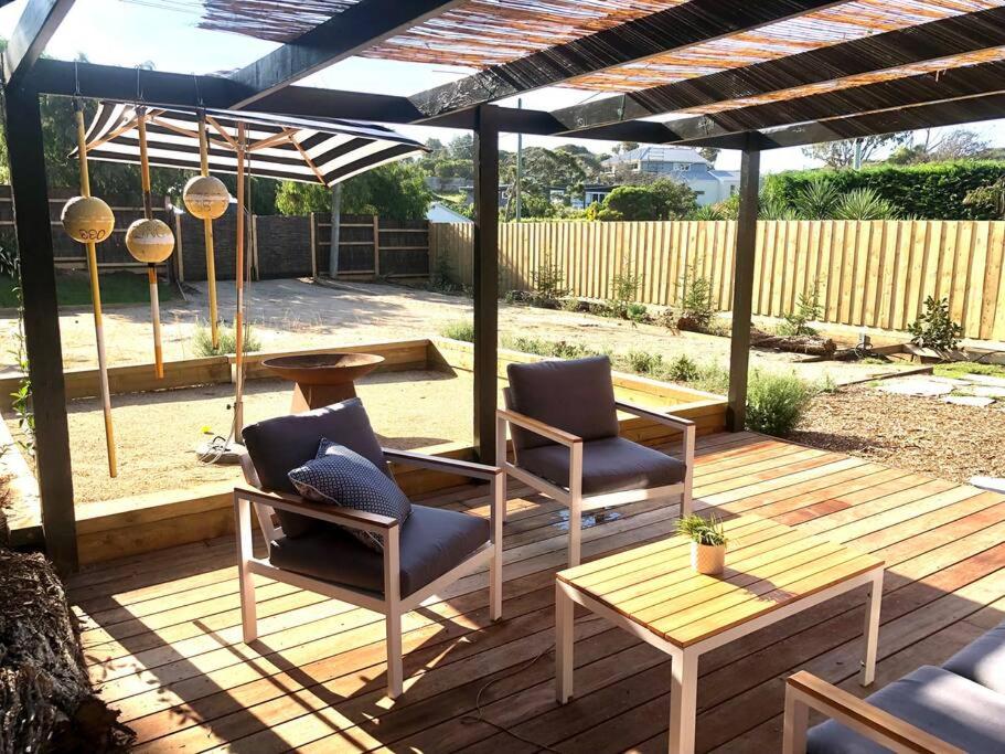 a patio with two chairs and a table under a pergola at Cosy Back Beach Hideaway with Fire Pit. in Portsea
