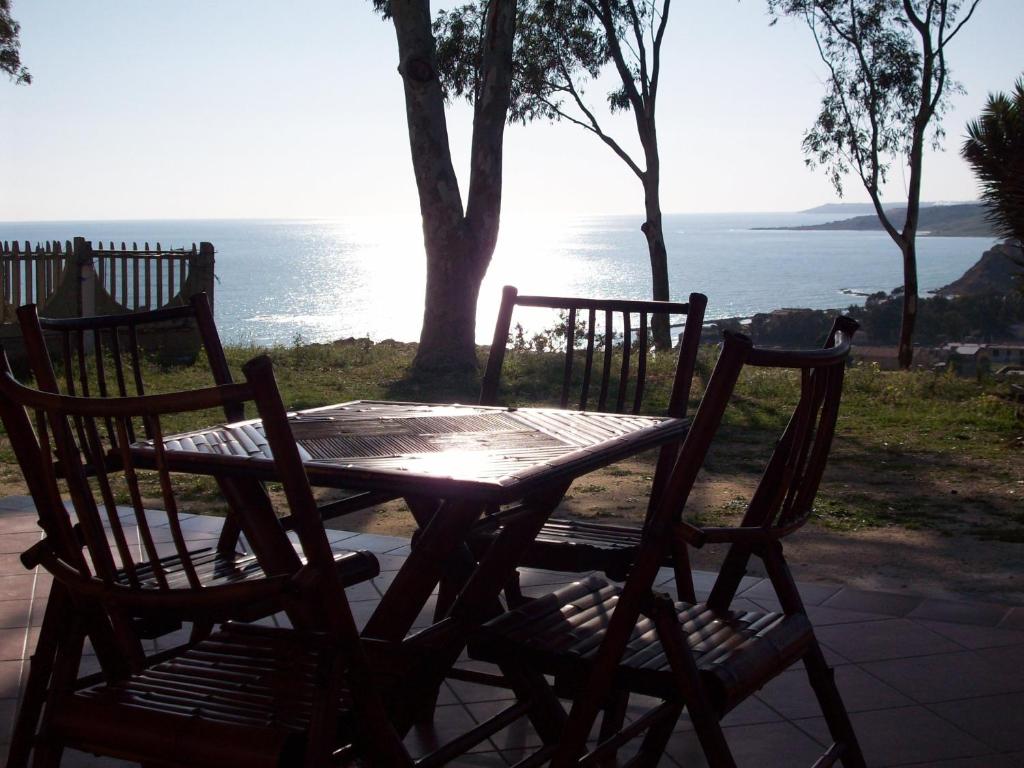 a wooden table and chairs with a view of the ocean at Kalypso in Sciacca