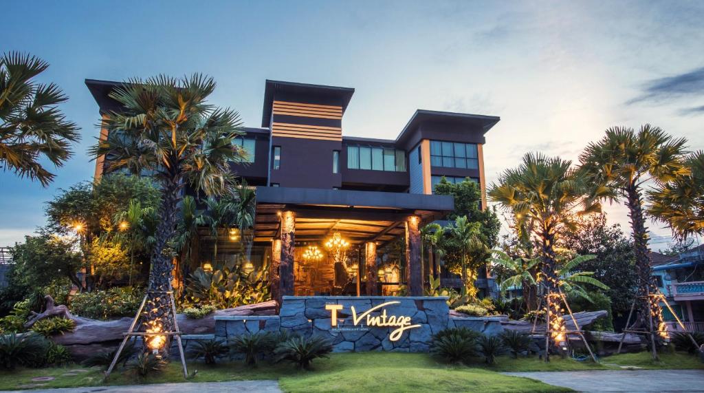 une grande maison avec des palmiers devant dans l'établissement T Vintage, à Bang Khla
