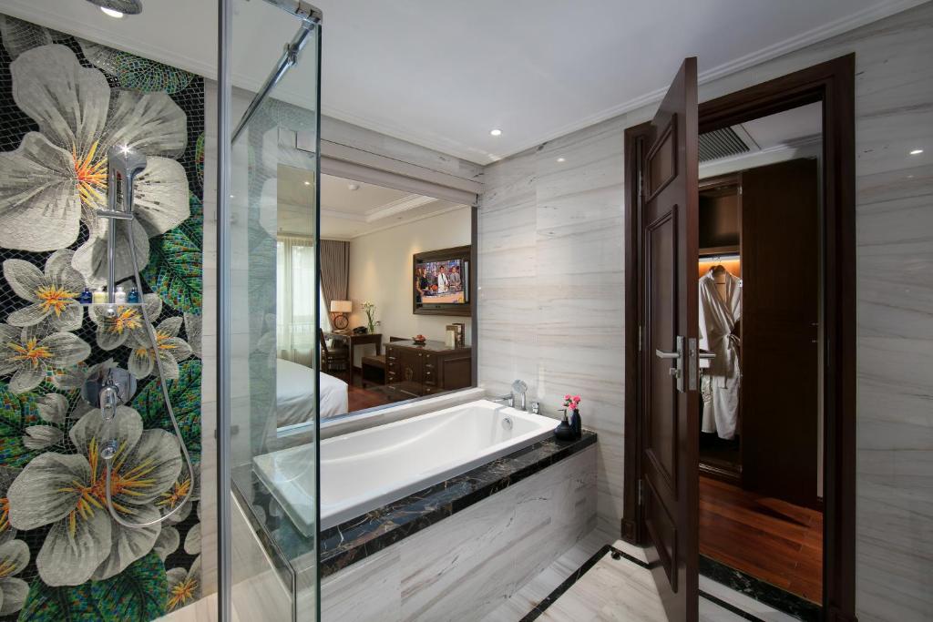 a bathroom with a tub and a glass shower at Lucien Hanoi Lakeside Hotel & Rooftop in Hanoi